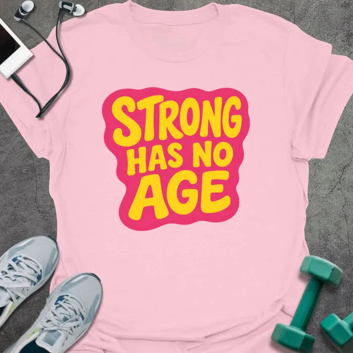 Light pink t-shirt printed with "STRONG HAS NO AGE" in yellow and pink, with badge graphic