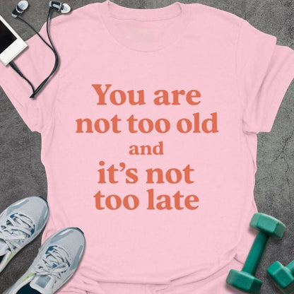 Light pink t-shirt printed with "You are not too old and it's not too late" in red