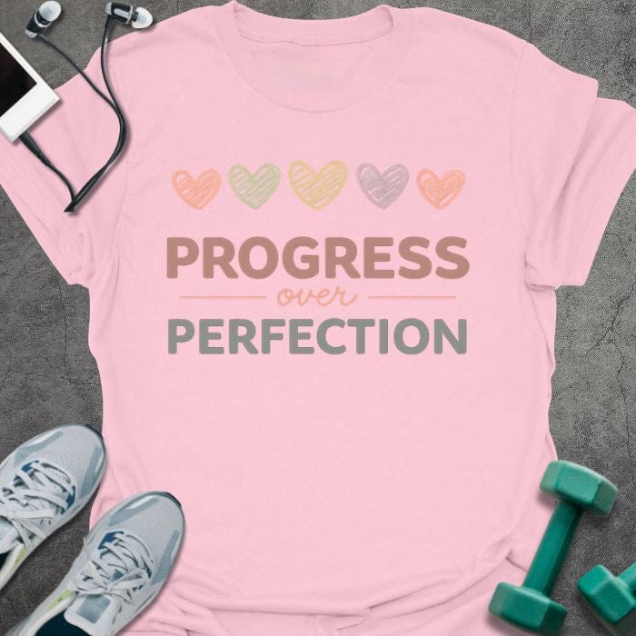 Light pink t-shirt printed with "PROGRESS over PERFECTION" in multi-color, with five hearts in pastel colors