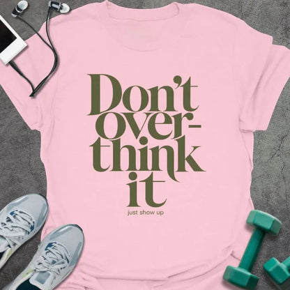 Light pink t-shirt printed with "Don't Over-think it just show up" in green and black
