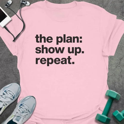 Light Pink t-shirt printed with "the plan: show up. repeat." in black lettering