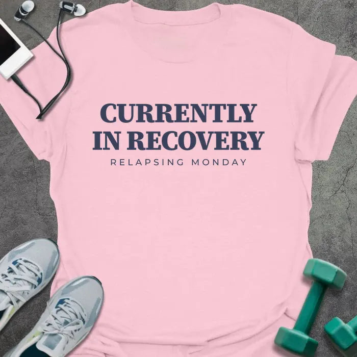 Light pink t-shirt printed with "CURRENTLY IN RECOVERY, RELAPSING MONDAY" in navy blue