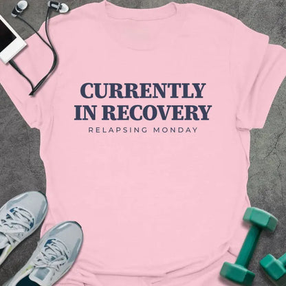 Light pink t-shirt printed with "CURRENTLY IN RECOVERY, RELAPSING MONDAY" in navy blue