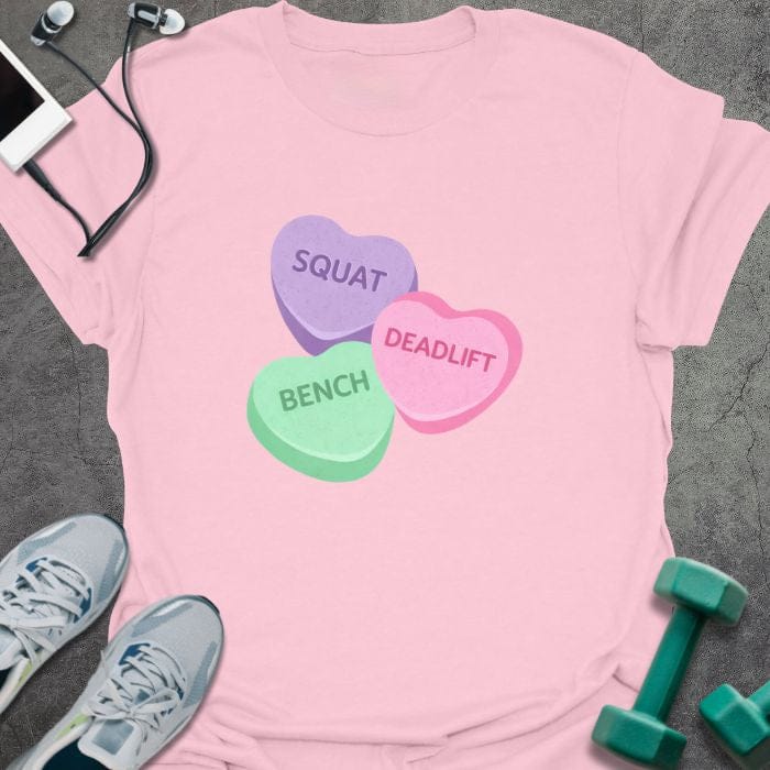 Light pink t-shirt printed with "Squat Bench Deadlift" in purple, green, pink, with three conversation candy hearts in purple, green, and pink