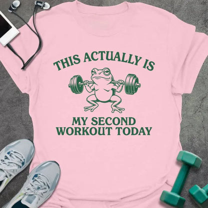 Light pink t-shirt printed with "This Actually is my Second Workout Today" in green, with an illustration of a frog lifting barbell
