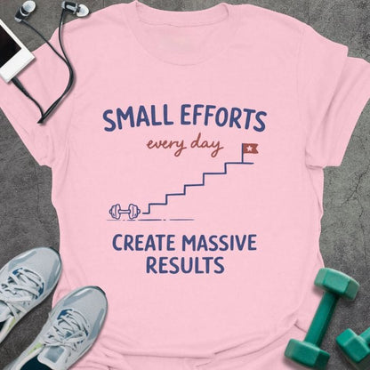 Light pink t-shirt printed with "SMALL EFFORTS every day CREATE MASSIVE RESULTS" in red and blue, with stairs and flag illustration