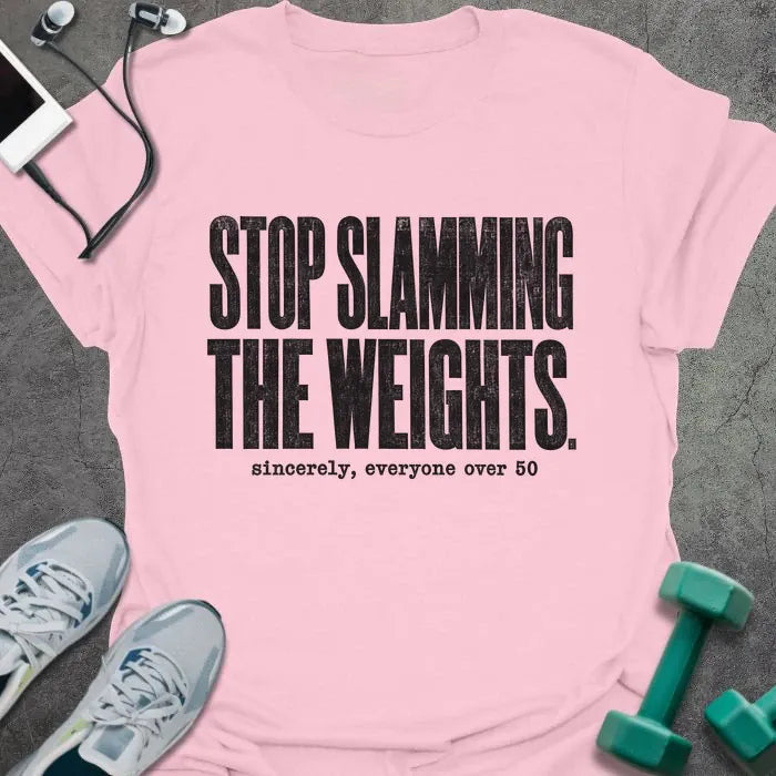 Light pink T-shirt printed with "STOP SLAMMING THE WEIGHTS. sincerely, everyone over 50" in black