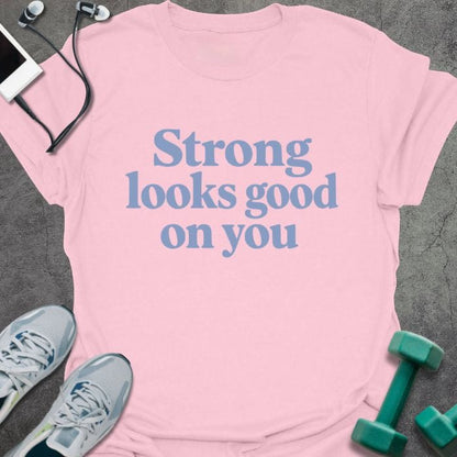 Light pink t-shirt printed with "Strong looks good on you" in blue