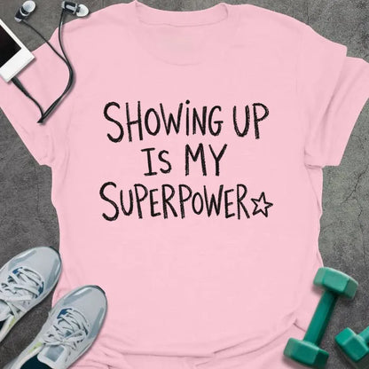 Light Pink t-shirt printed with "SHOWING UP IS MY SUPERPOWER" in black handwritten lettering, with a star outline