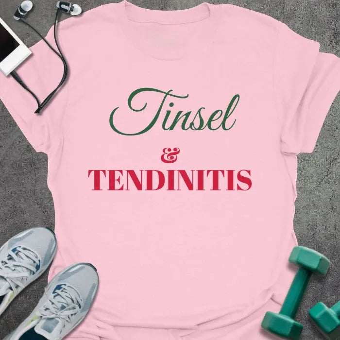 Light pink t-shirt printed with "Tinsel & Tendinitis" in green and red