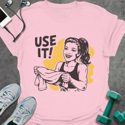 Light pink t-shirt printed with "Use it!" in black and yellow, with a retro-style woman illustration holding a towel