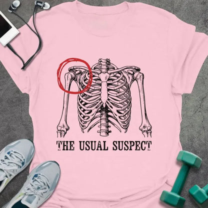 Light pink t-shirt printed with "The Usual Suspect" in white and red, with a skeleton anatomy illustration highlighting the heart in red