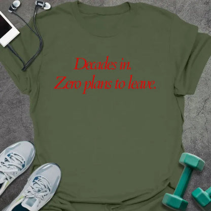 Military green t-shirt printed with "Decades in. Zero plans to leave." in red