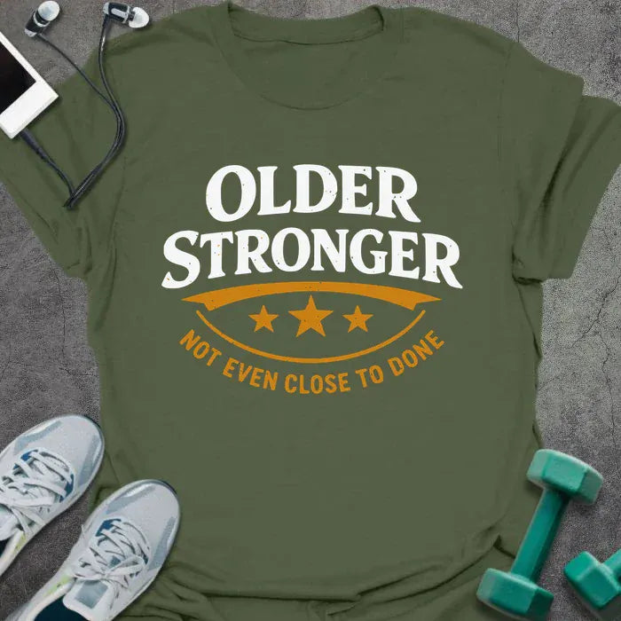 Military green t-shirt printed with "Older Stronger Not Even Close to Done" in white and orange, with a scoreboard showing three stars