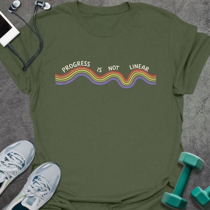 Military green t-shirt printed with "Progress is Not Linear" in white, rainbow, with a wavy rainbow line