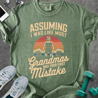 Moss t-shirt printed with "Assuming I Was Like Most Grandmas Was Your First Mistake" in white and gold, with a grandma lifting dumbbells graphic
