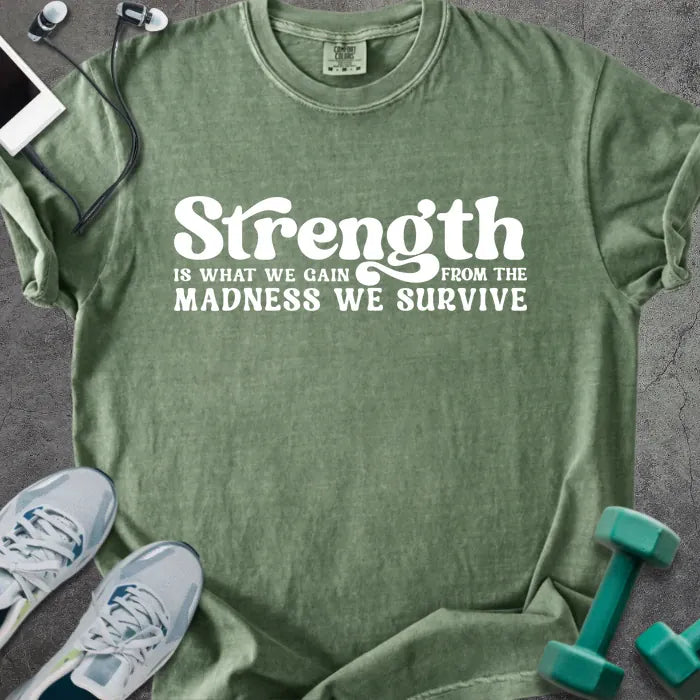 Moss t-shirt printed with "Strength is WHAT WE GAIN FROM THE MADNESS WE SURVIVE" in white