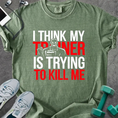 Moss t-shirt printed with "I Think my Trainer is Trying to Kill Me" in red and white, with a trainer figure