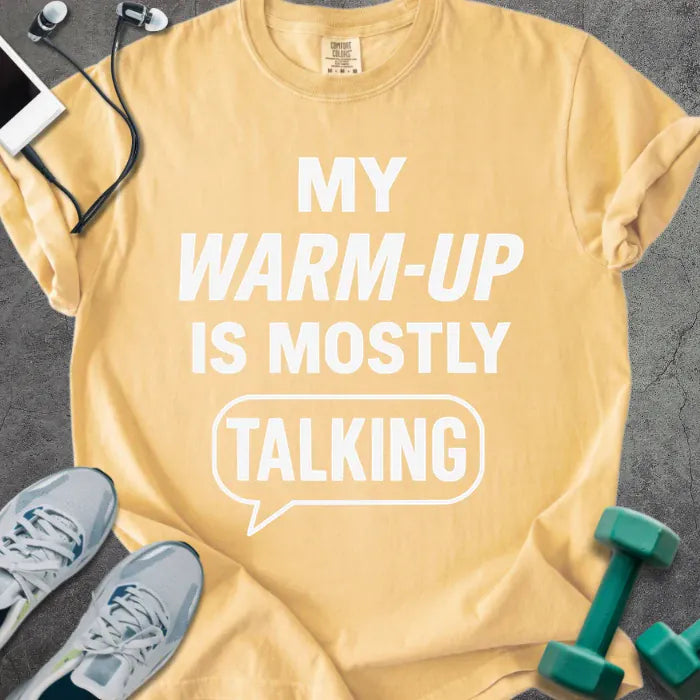 Mustard t-shirt printed with "My Warm-up is Mostly Talking" in white, with a speech bubble graphic