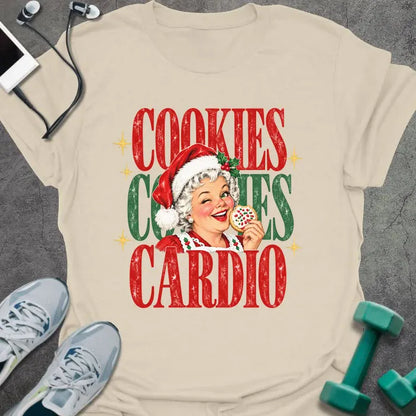 Natural t-shirt printed with "COOKIES COOKIES CARDIO" in red and green, with a vintage Mrs. Claus in a Santa hat winking and holding a frosted cookie