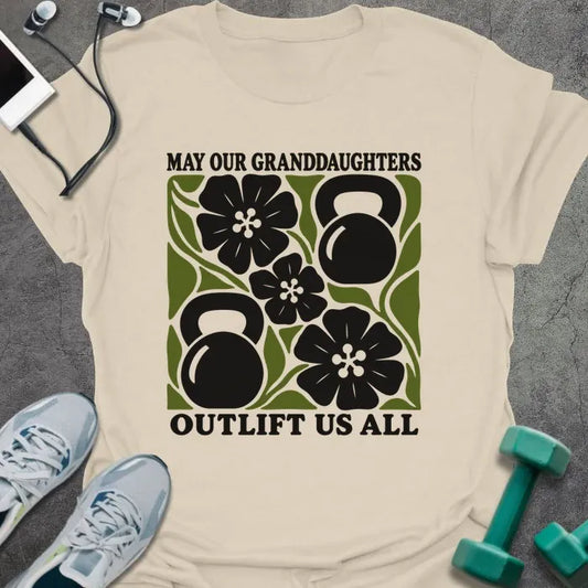 Natural t-shirt printed with "MAY OUR GRANDDAUGHTERS OUTLIFT US ALL", with four black flowers and two kettlebells on a green square