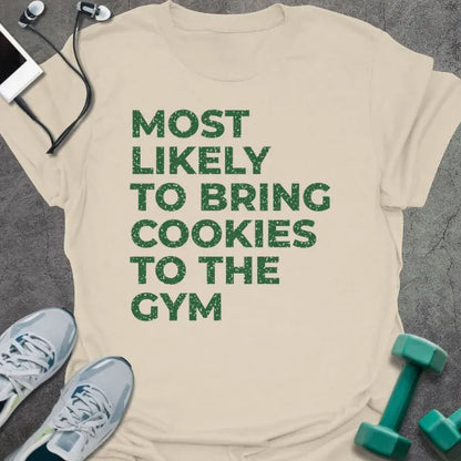 Natural t-shirt printed with "MOST LIKELY TO BRING COOKIES TO THE GYM" in green