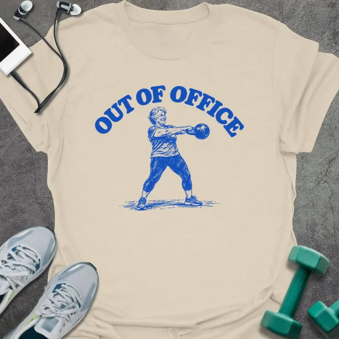 Natural t-shirt printed with "OUT OF OFFICE" in blue, with a sketch of an older woman swinging a kettlebell