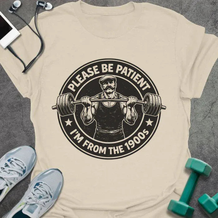 Cream t-shirt printed with "Please Be Patient I'm From the 1900s" in black, with a barbells and a retro strongman illustration
