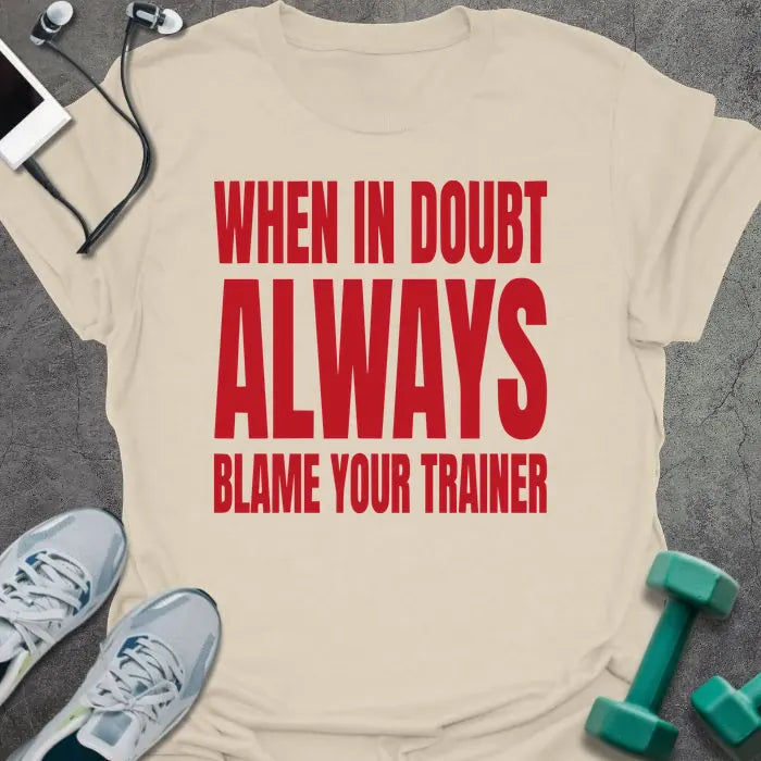 Cream t-shirt printed with "When in Doubt Always Blame Your Trainer" in red and white