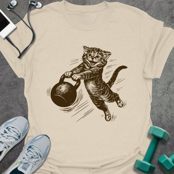 Cream t-shirt with a cat swinging a kettlebell in brown, tan