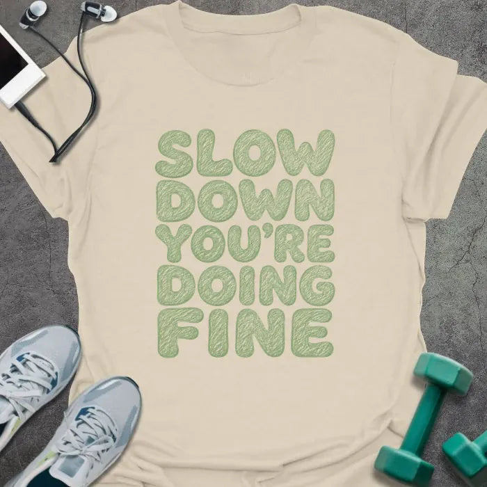 Natural t-shirt printed with "SLOW DOWN YOU'RE DOING FINE" in green