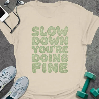 Natural t-shirt printed with "SLOW DOWN YOU'RE DOING FINE" in green