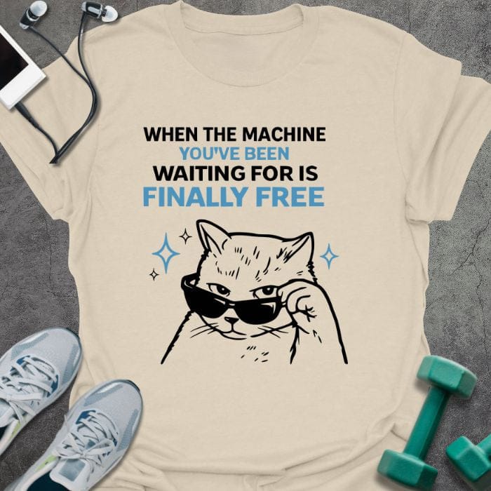 Cream t-shirt printed with "When the Machine You've Been Waiting for is Finally Free" in black, with an illustration of a cat wearing sunglasses
