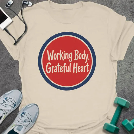 Natural t-shirt printed with "Working Body. Grateful Heart." in white script lettering inside a red circle with navy blue border
