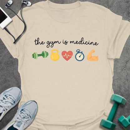 Cream t-shirt printed with "the gym is medicine" in multicolor, with emoji icons of gym equipment