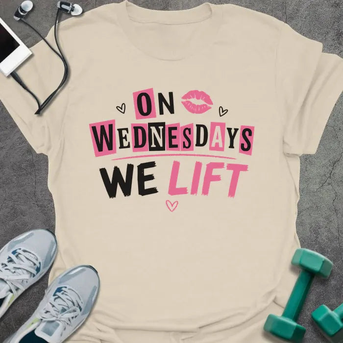 Cream t-shirt printed with "On Wednesdays We Lift" in pink and black, with an illustration of lips and hearts