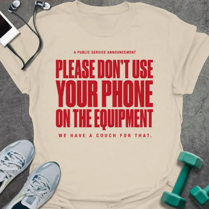 Cream t-shirt printed with "A Public Service Announcement Please Don't Use Your Phone on the Equipment We Have a Couch for That." in red