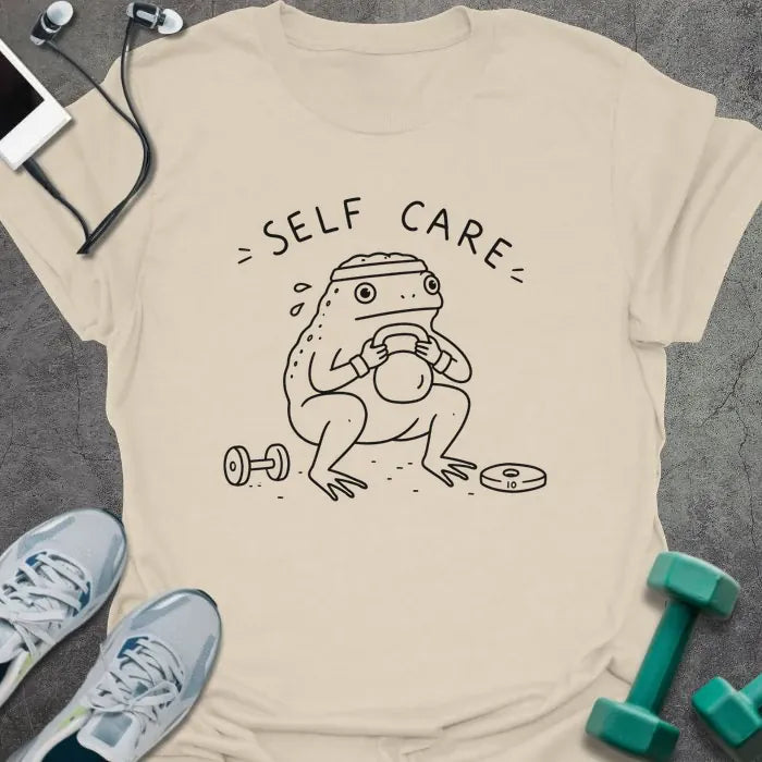 Natural t-shirt printed with "= SELF CARE =" in black, with figure exercising with kettlebell and dumbbells