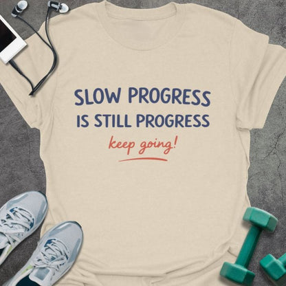 Cream t-shirt printed with "SLOW PROGRESS IS STILL PROGRESS keep going!" in red