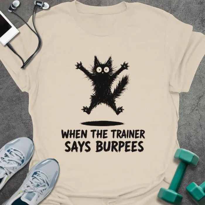 Natural t-shirt printed with "WHEN THE TRAINER SAYS BURPEES" in black italic lettering, with a black freaked-out cat with wide eyes