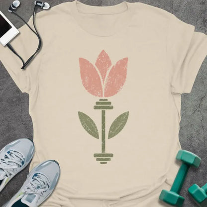 Cream t-shirt with an illustration of tulip flowers surrounding a barbell in coral and green