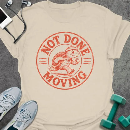 Natural t-shirt printed with "NOT DONE MOVING" in coral, with running turtle in circle