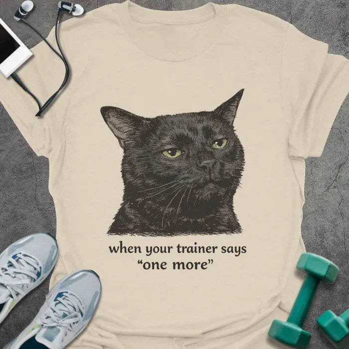 Cream t-shirt printed with "when your trainer says "one more", with a realistic unamused black cat portrait