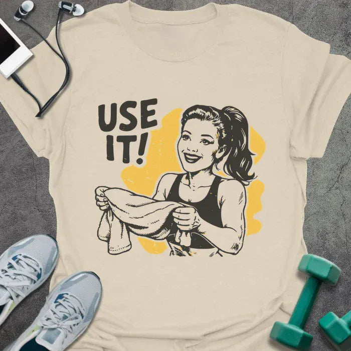 Cream t-shirt printed with "Use it!" in black and yellow, with a retro-style woman illustration holding a towel