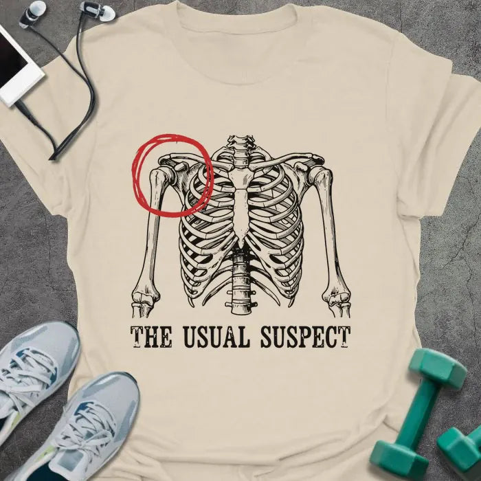 Cream t-shirt printed with "The Usual Suspect" in white and red, with a skeleton anatomy illustration highlighting the heart in red