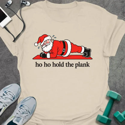 Natural t-shirt printed with "ho ho hold the plank" in black, with Santa holding a plank on a red mat