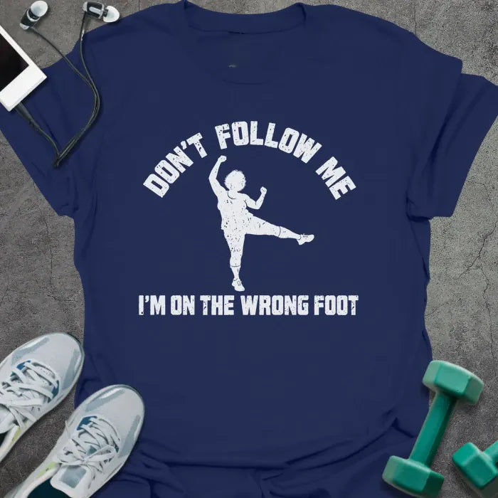 Navy t-shirt printed with "DON'T FOLLOW ME, I'M ON THE WRONG FOOT" in white, with an older woman doing an aerobics kick