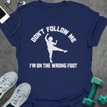 Navy t-shirt printed with "DON'T FOLLOW ME, I'M ON THE WRONG FOOT" in white, with an older woman doing an aerobics kick