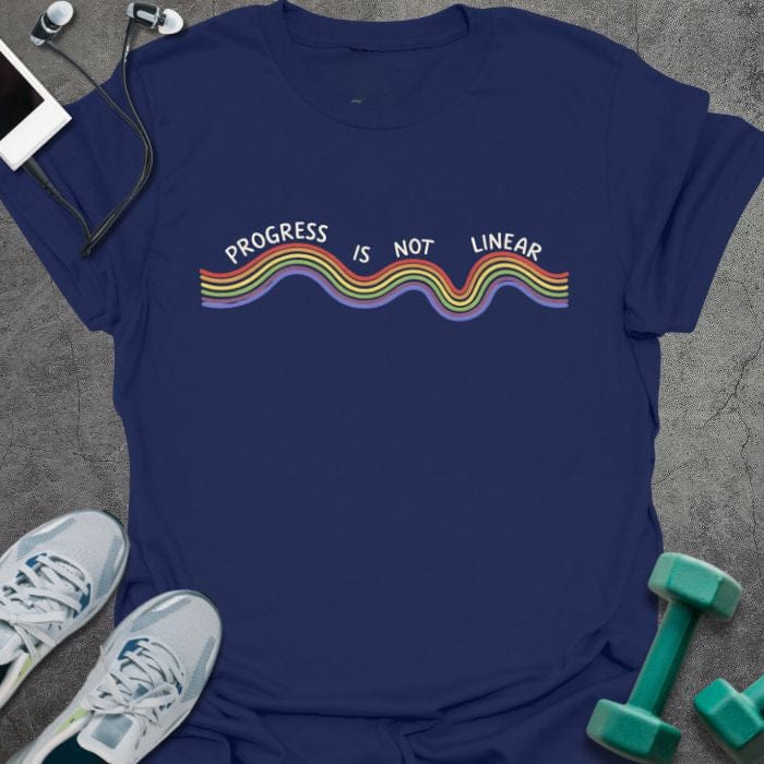 Navy t-shirt printed with "Progress is Not Linear" in white, rainbow, with a wavy rainbow line
