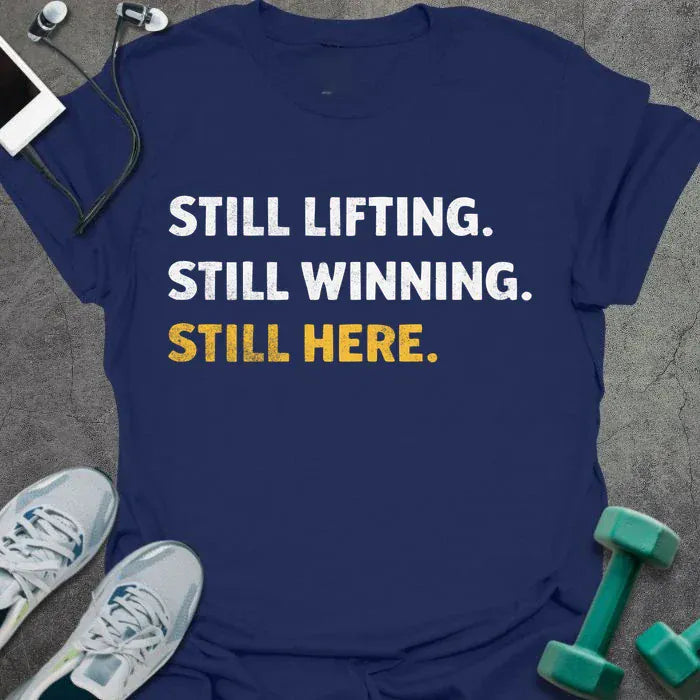 Navy t-shirt printed with "Still Lifting. Still Winning. Still Here." in white and yellow